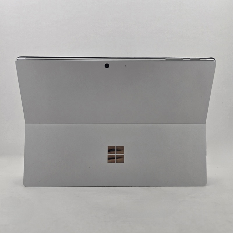 نمای پشت تبلت استوک مایکروسافت Surface Pro 5 با بدنه‌ای از آلیاژ منیزیم نقره‌ای، پایه نگهدارنده تاشو تا 165 درجه، و نوار پلاستیکی در لبه بالایی برای آنتن‌دهی WiFi.
